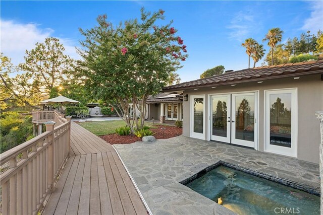 wooden deck featuring a hot tub, a patio, and french doors