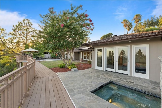 rear view of property with a jacuzzi, a tile roof, french doors, a wooden deck, and stucco siding