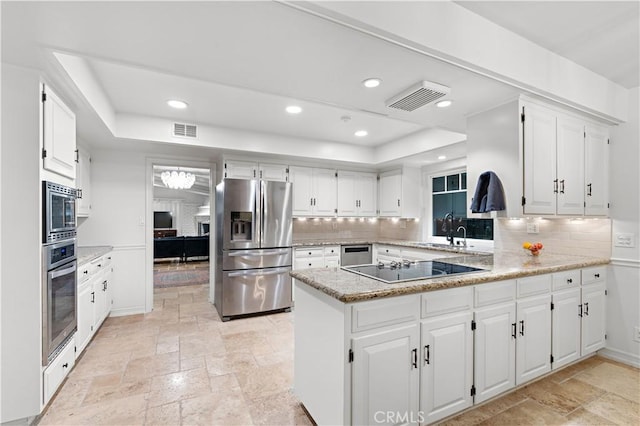 kitchen featuring sink, white cabinets, decorative backsplash, kitchen peninsula, and stainless steel appliances