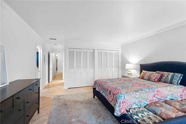 bedroom with multiple closets, visible vents, crown molding, and parquet flooring