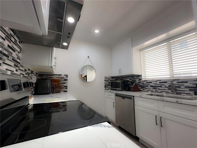 kitchen with light stone counters, sink, stainless steel appliances, and white cabinets