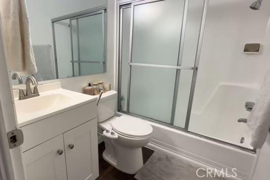 full bathroom featuring toilet, vanity, and shower / bath combination with glass door