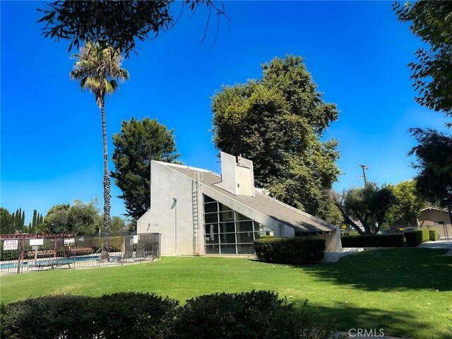 rear view of property with a community pool and a lawn