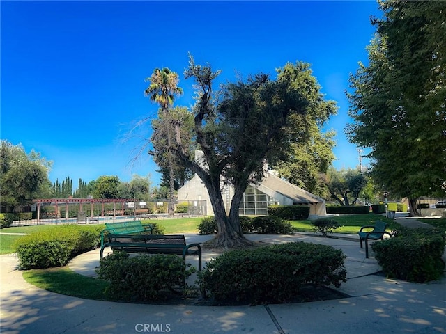 view of property's community featuring a pergola and a lawn