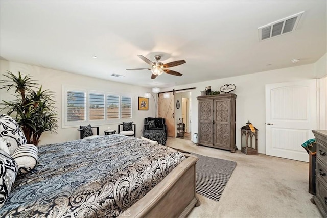 carpeted bedroom featuring a barn door and ceiling fan