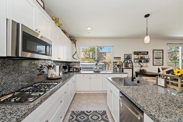 kitchen featuring white cabinets, a healthy amount of sunlight, light stone countertops, and stainless steel appliances