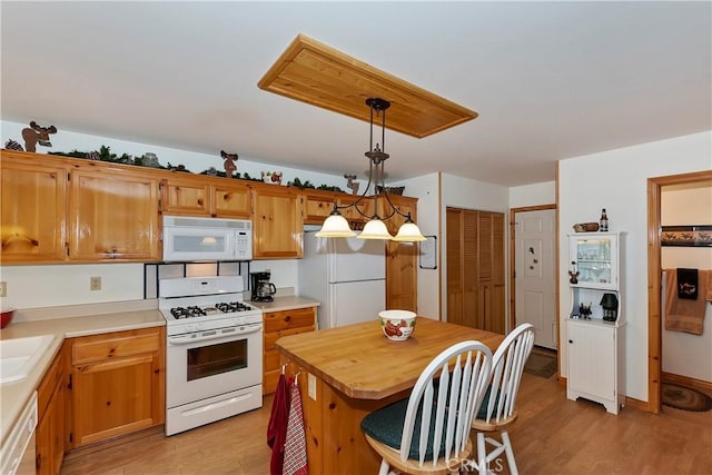 kitchen featuring light hardwood / wood-style flooring, hanging light fixtures, and white appliances