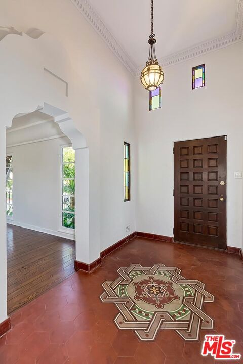 foyer with a towering ceiling, dark wood-type flooring, and ornamental molding