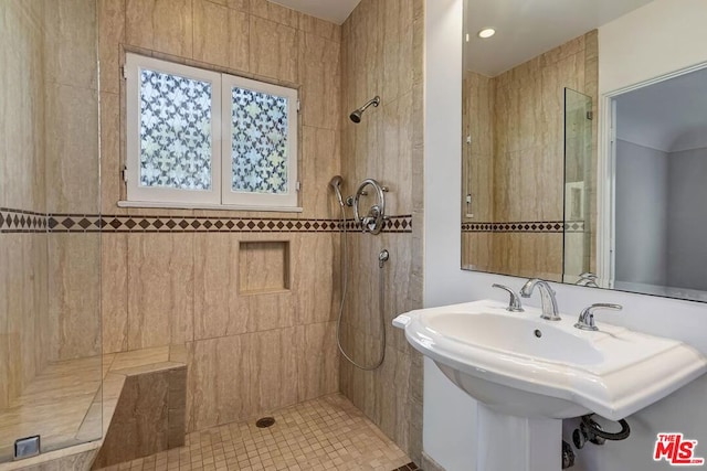 bathroom with tile patterned floors, tiled shower, and sink