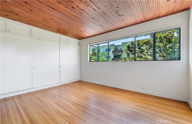 unfurnished room with light wood-type flooring and wooden ceiling