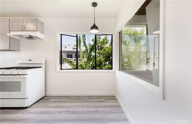 kitchen with gray cabinets, light hardwood / wood-style flooring, white gas range, and a wealth of natural light