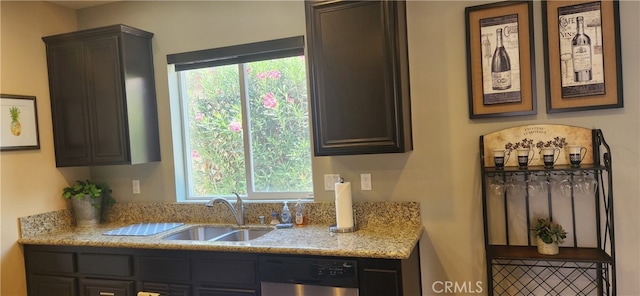 kitchen with a healthy amount of sunlight, dishwasher, sink, and light stone countertops