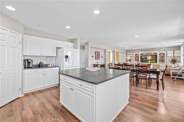 kitchen featuring white cabinetry, white fridge with ice dispenser, a center island, and light wood-type flooring