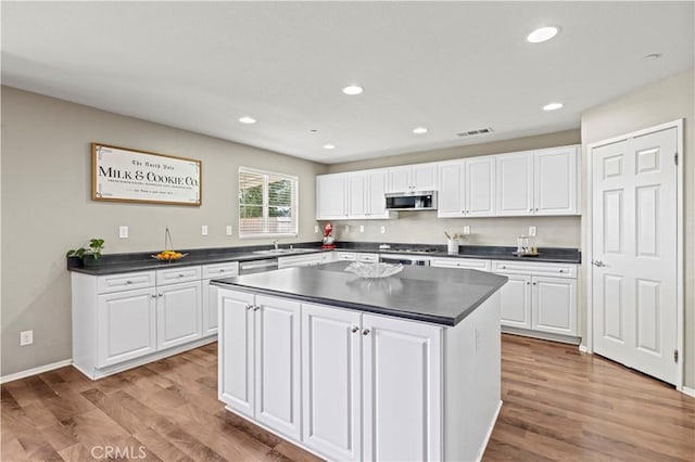 kitchen featuring appliances with stainless steel finishes, sink, light hardwood / wood-style flooring, white cabinets, and a center island