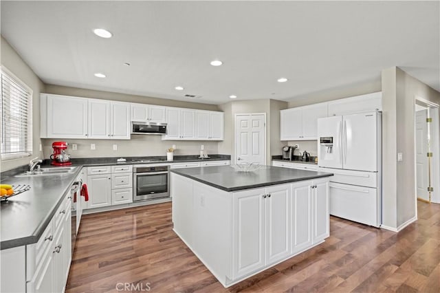 kitchen with stainless steel appliances, sink, white cabinets, a center island, and dark hardwood / wood-style floors