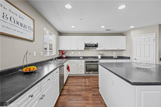 kitchen with white cabinets, appliances with stainless steel finishes, dark hardwood / wood-style floors, and sink