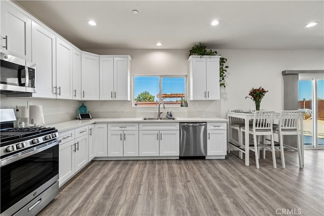 kitchen with appliances with stainless steel finishes, a healthy amount of sunlight, white cabinetry, and sink