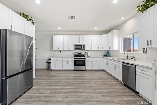 kitchen featuring stainless steel appliances, white cabinets, and light wood-type flooring