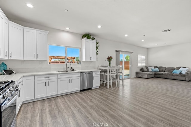 kitchen featuring white cabinets, appliances with stainless steel finishes, sink, and light hardwood / wood-style flooring