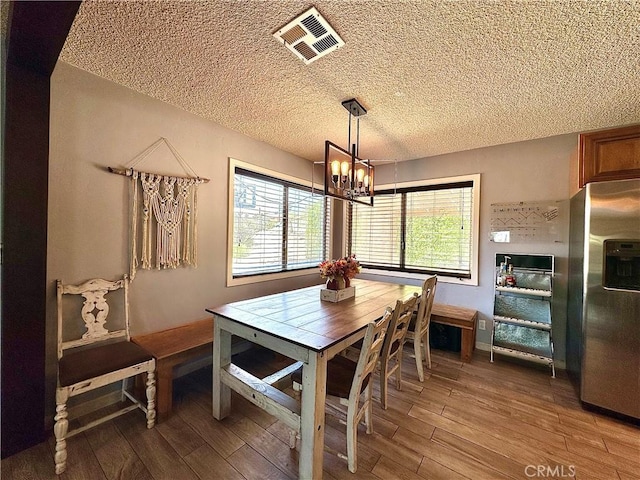 dining room with wood-type flooring, a notable chandelier, and a textured ceiling