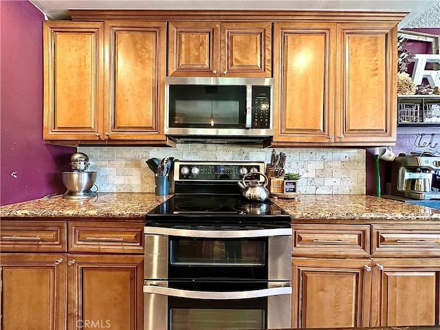 kitchen with appliances with stainless steel finishes, tasteful backsplash, and light stone countertops