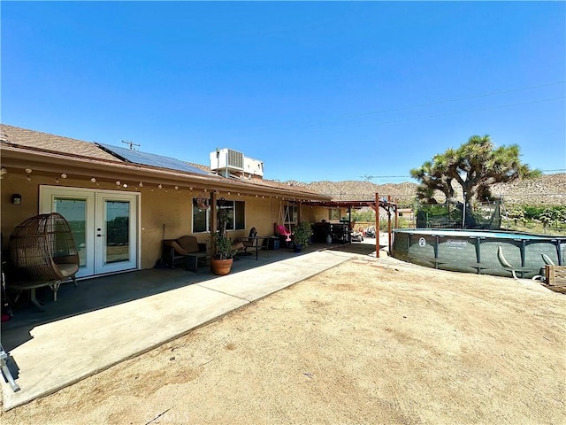 rear view of house with a patio area, french doors, and solar panels