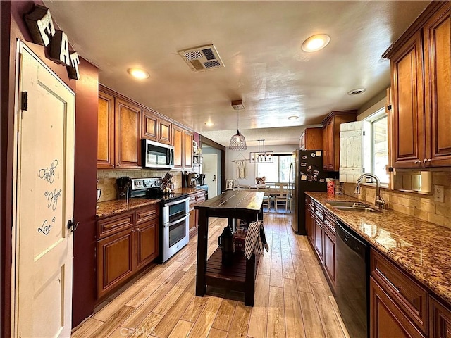 kitchen featuring stainless steel appliances, light hardwood / wood-style flooring, hanging light fixtures, and sink