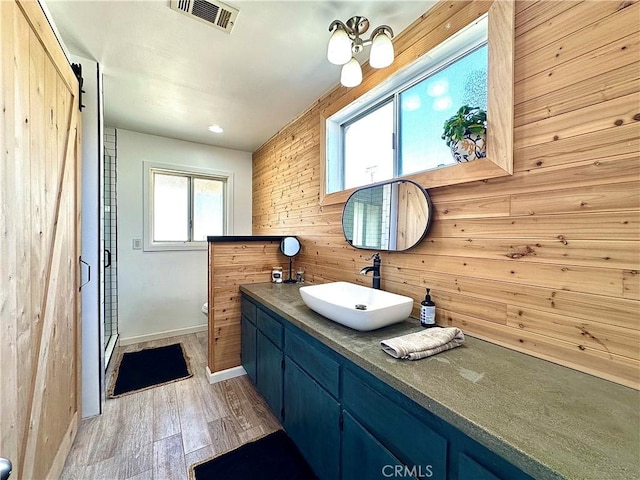 bathroom with hardwood / wood-style flooring, plenty of natural light, a shower with door, and wood walls