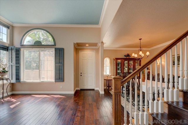 foyer entrance featuring a textured ceiling, ornamental molding, dark hardwood / wood-style floors, and a notable chandelier