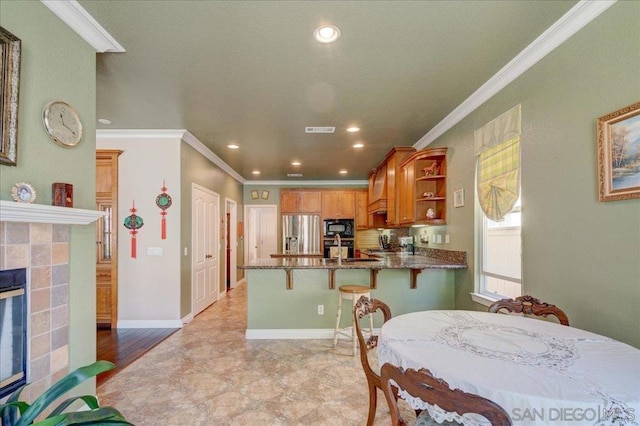 dining area with a tile fireplace and crown molding