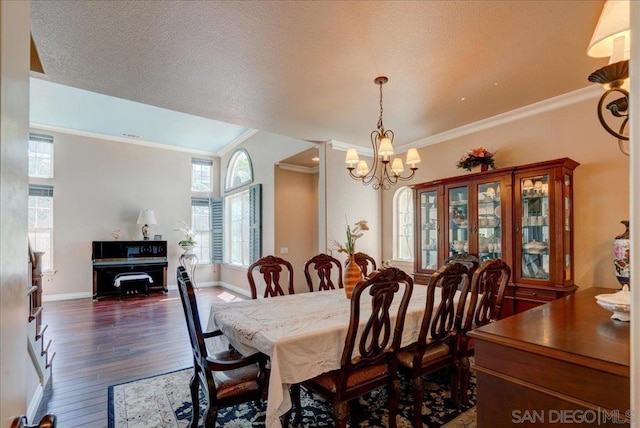 dining space with a textured ceiling, crown molding, dark hardwood / wood-style floors, and a chandelier