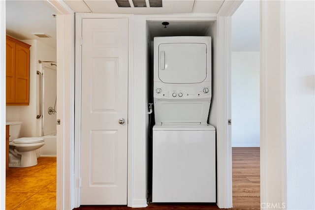 laundry room with light wood-type flooring and stacked washing maching and dryer