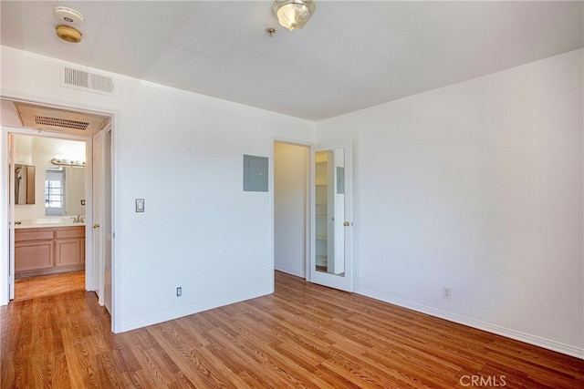 unfurnished bedroom featuring electric panel, light hardwood / wood-style flooring, and sink