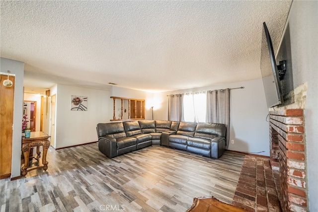 living room featuring a brick fireplace, a textured ceiling, and hardwood / wood-style flooring