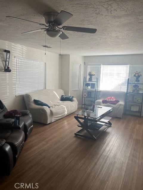 living room featuring ceiling fan, wood-type flooring, and a textured ceiling