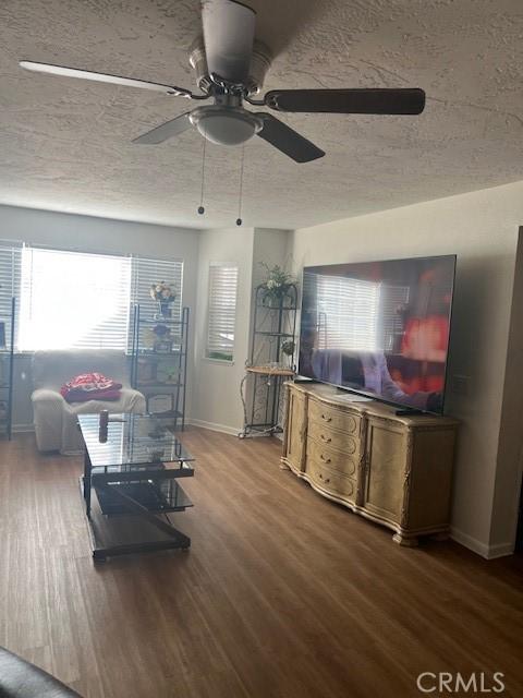 living room featuring hardwood / wood-style flooring, ceiling fan, and a textured ceiling