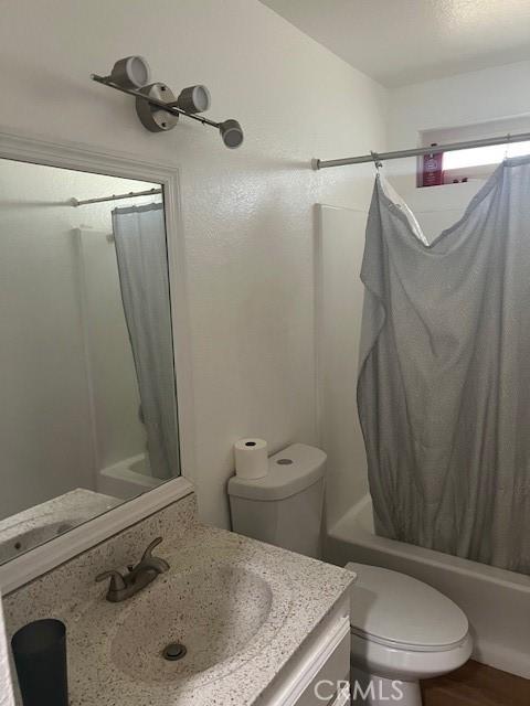 full bathroom featuring vanity, shower / tub combo, hardwood / wood-style flooring, and toilet