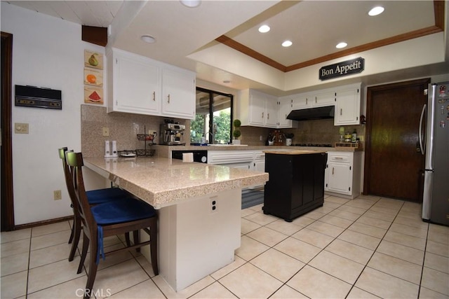 kitchen featuring white cabinetry, a breakfast bar, stainless steel fridge, and a center island