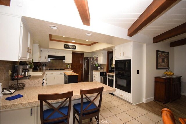 kitchen with white cabinetry, sink, kitchen peninsula, light hardwood / wood-style floors, and black appliances