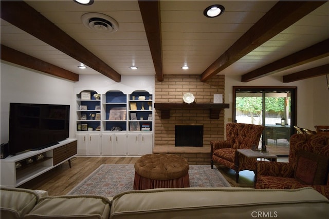 living room featuring beam ceiling, a fireplace, and light hardwood / wood-style flooring