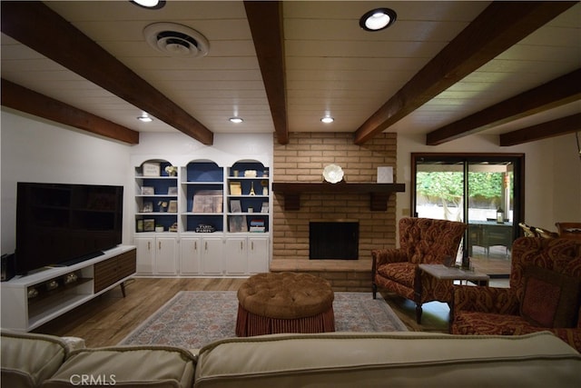 living room featuring a brick fireplace, light hardwood / wood-style floors, and beamed ceiling