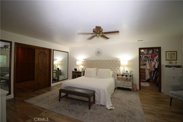 bedroom featuring ceiling fan, a spacious closet, and dark hardwood / wood-style floors