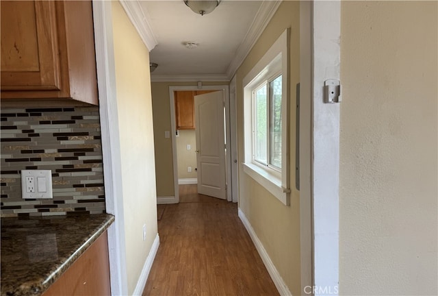 corridor with light wood-type flooring and crown molding