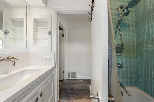 bathroom featuring hardwood / wood-style flooring, tiled shower / bath, and vanity