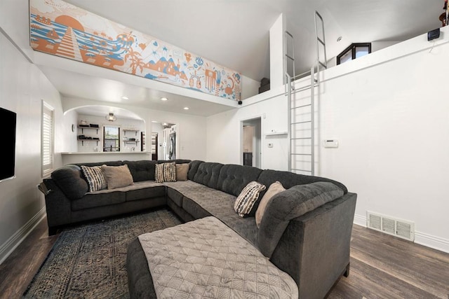 living room featuring dark wood-type flooring and a high ceiling