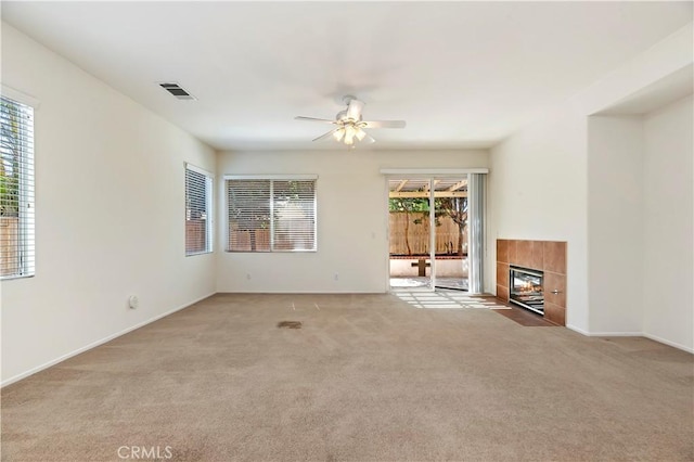 unfurnished living room with a fireplace, ceiling fan, and light carpet