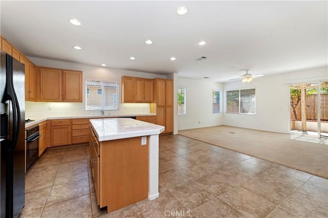 kitchen with black appliances, tile counters, plenty of natural light, and light colored carpet