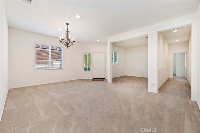 carpeted spare room with a chandelier