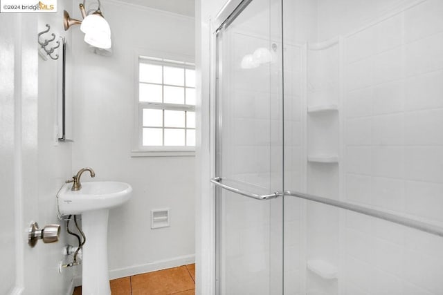 bathroom featuring tile patterned flooring, crown molding, an enclosed shower, and sink