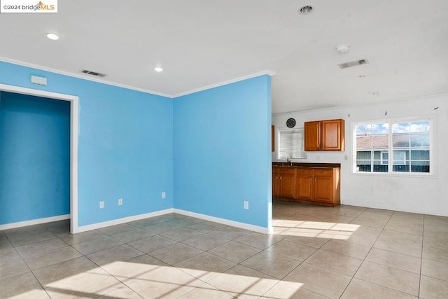 unfurnished living room with crown molding, sink, and light tile patterned flooring